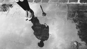 A person's reflection showing in a puddle