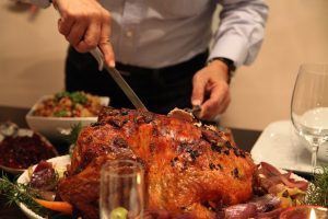 a man cutting a roasted turkey at the dinner table